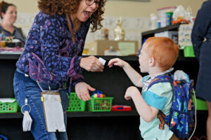 Young boy gives his excited teacher a picture to communicate
