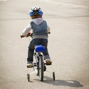 Child riding bicycle with training wheels.
