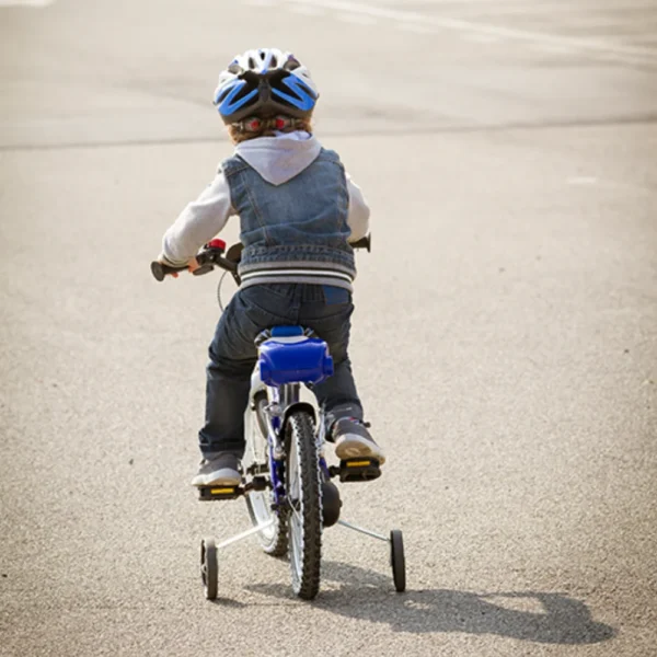 Child riding bicycle with training wheels.