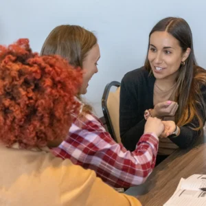 Three women conversing, seated at table.